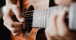 Hands playing guitar strings