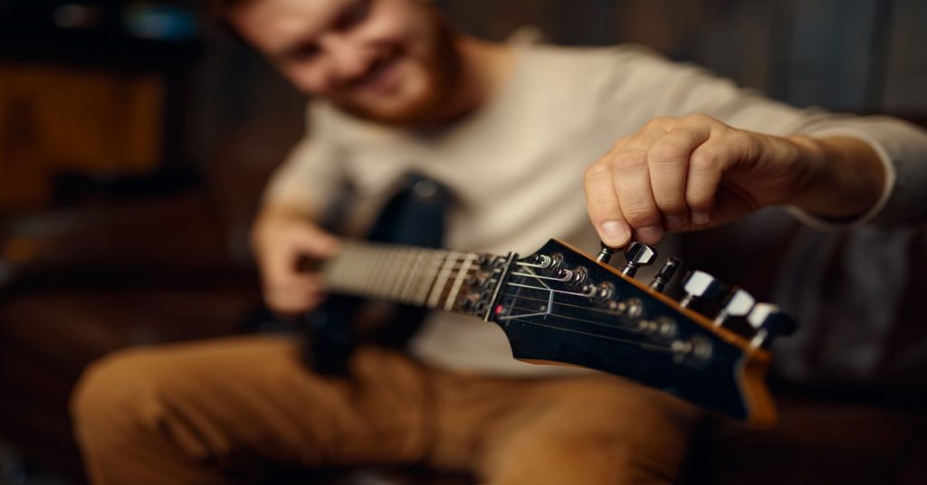 guitarist tune guitar before playing