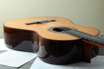 A Classical guitar on a table with music sheets